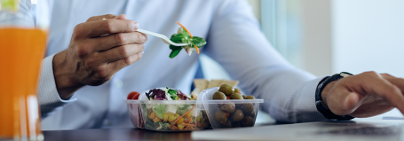 Employee eating healthy lunch at desk while working on laptop, illustrating UK break laws.