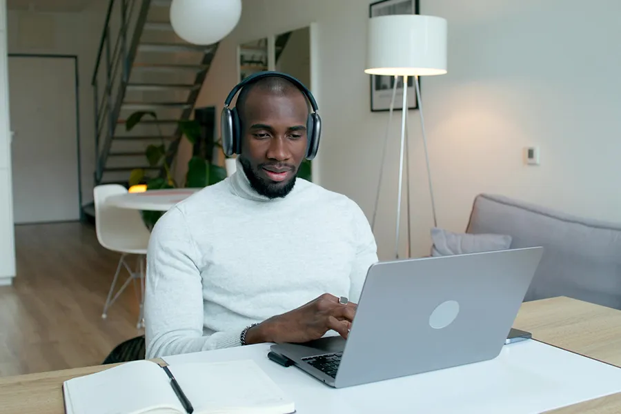 A man wearing a helmet working at his computer at home