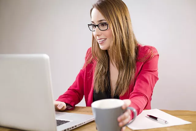 Woman having coffee and working on a laptop