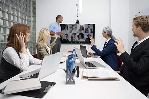 Hybrid business meeting with remote teams on screen, illustrating Kelio scalable workforce management for multi-site SMEs
